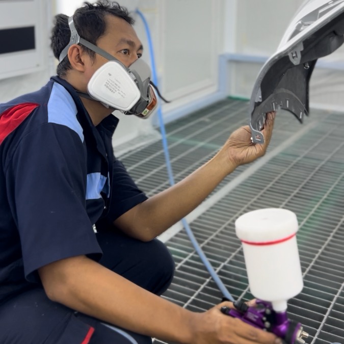 Teknisi melakukan inspeksi hasil finishing panel kendaraan